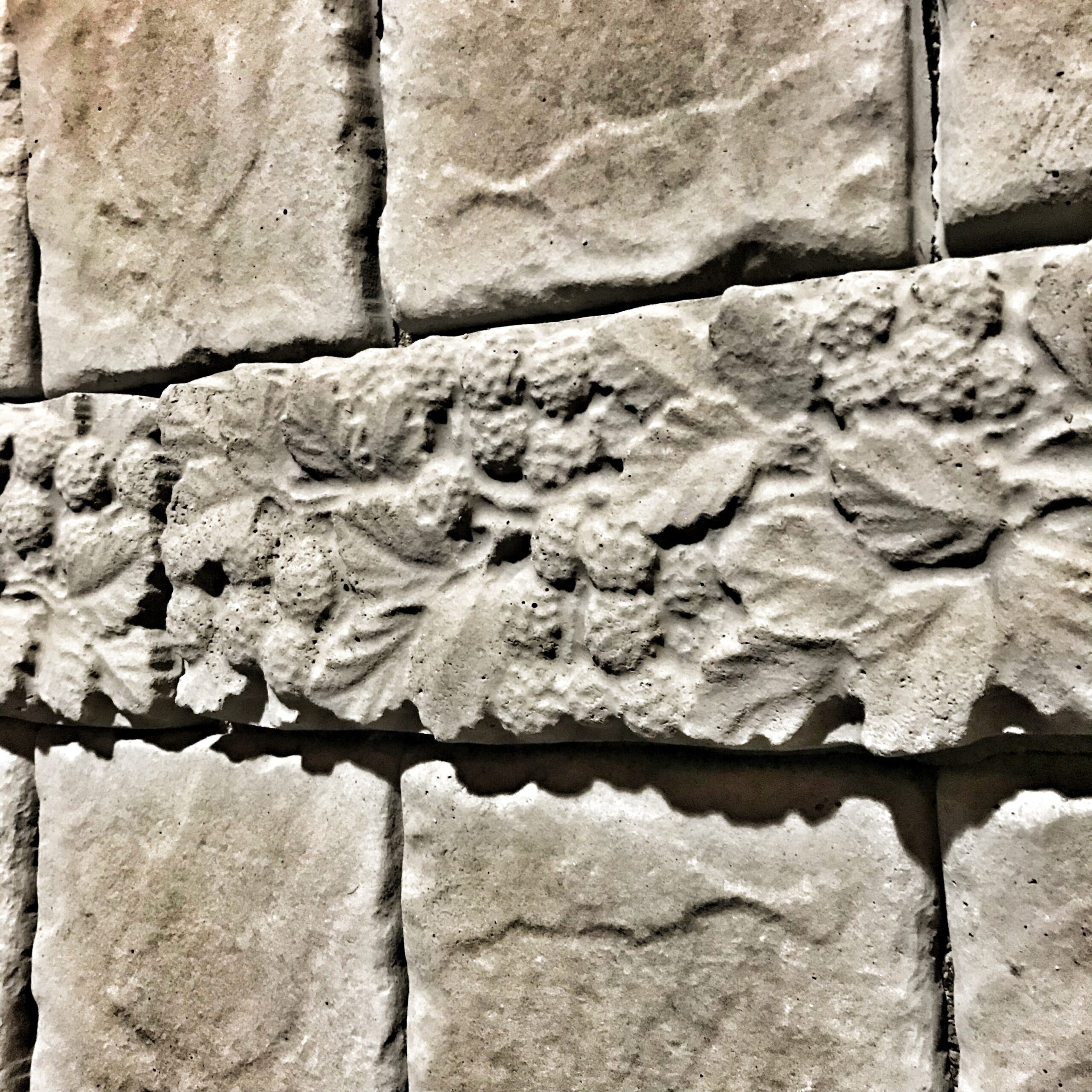 068a63f7 b98b 41eb 8835 b6a76e1de4c9.jpg Cast concrete raspberry-pattern decorative strip installed against a stone wall