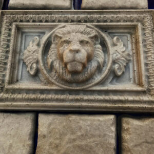 Finished weathered concrete horizontal lion wall relief installed on a stone wall